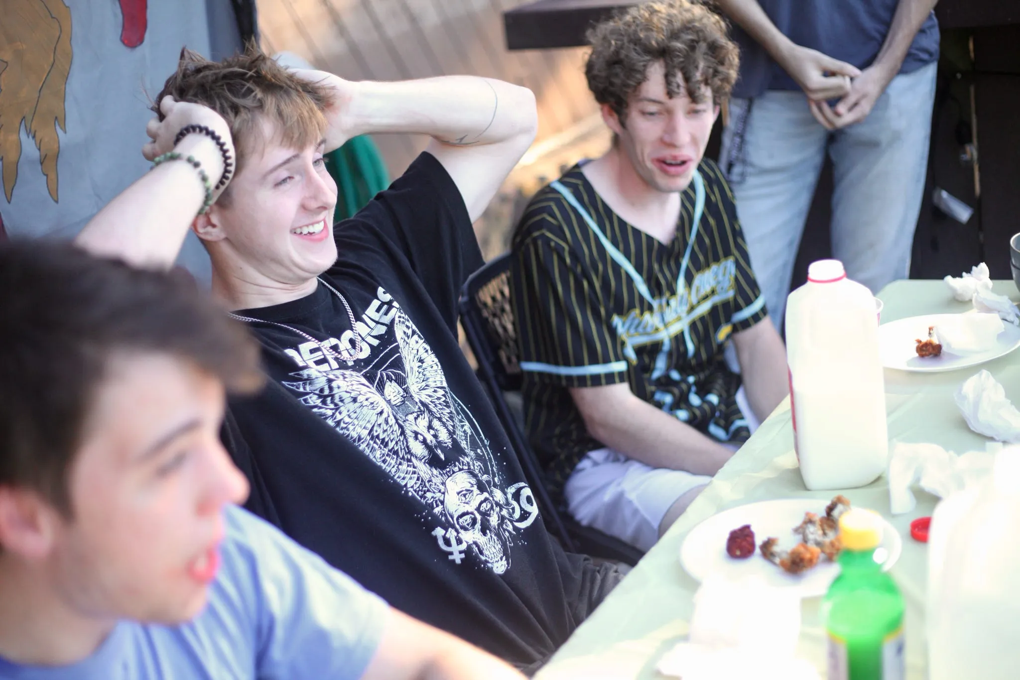Brothers laughing around a table with chicken wings at a Deaf Child Hope fundraiser