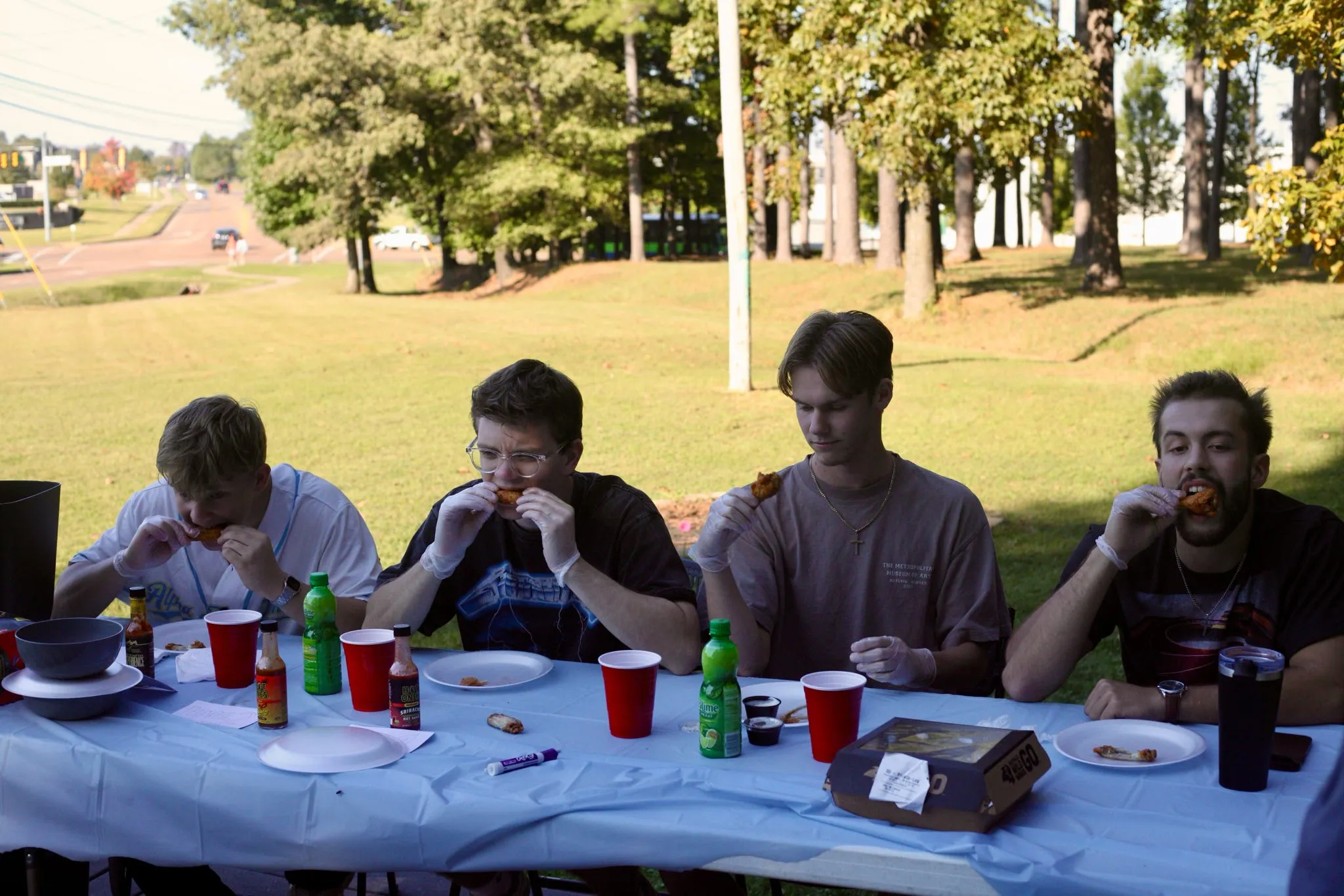 Four brothers eating chicken wings at an outdoor table during a Deaf Child Hope fundraiser