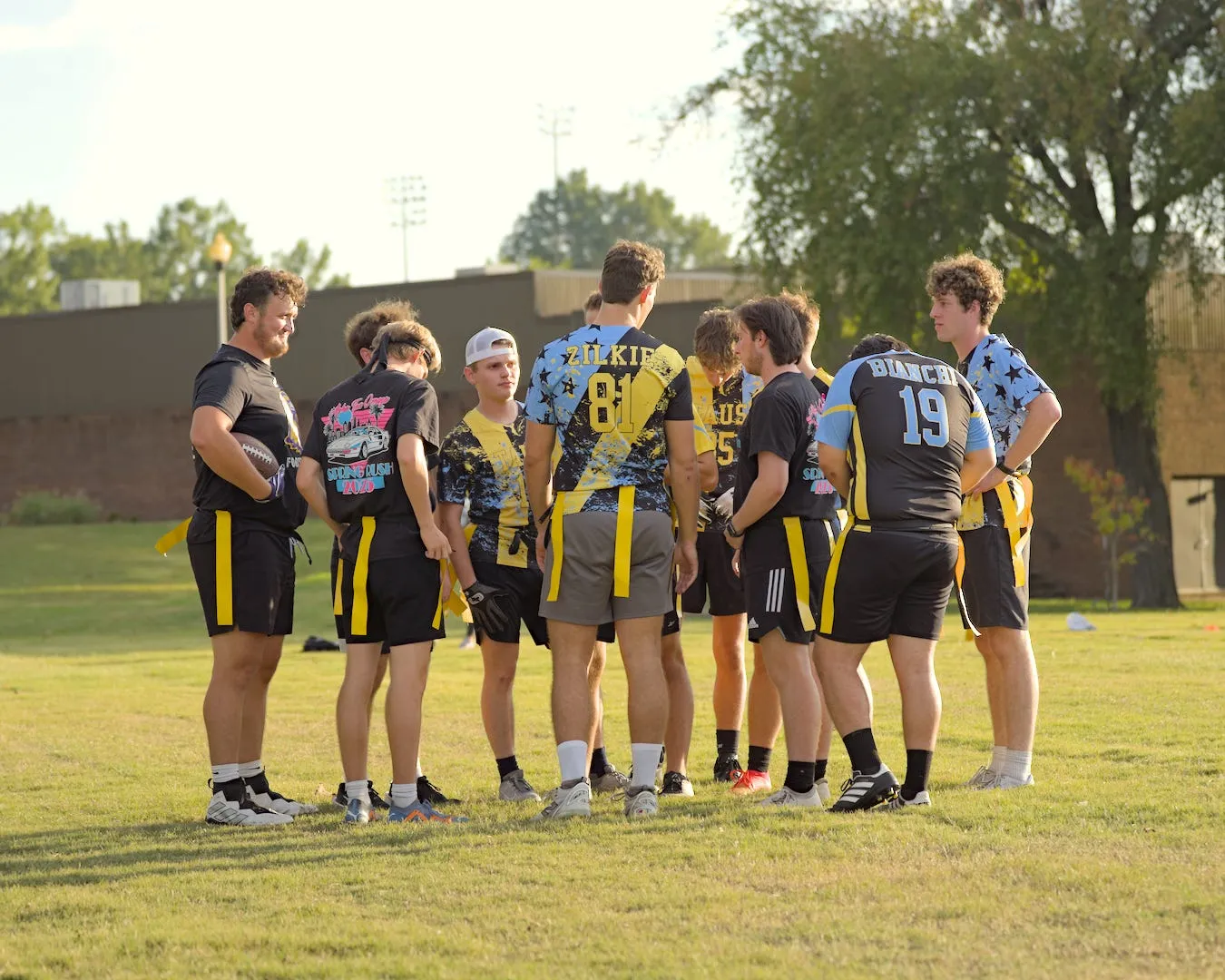 Brothers huddled together during a flag football game in black, gold, and blue jerseys